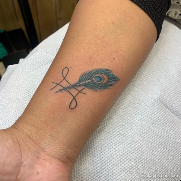 Small Peacock Feather and Symbol Tattoo Idea Delicate Wrist Design